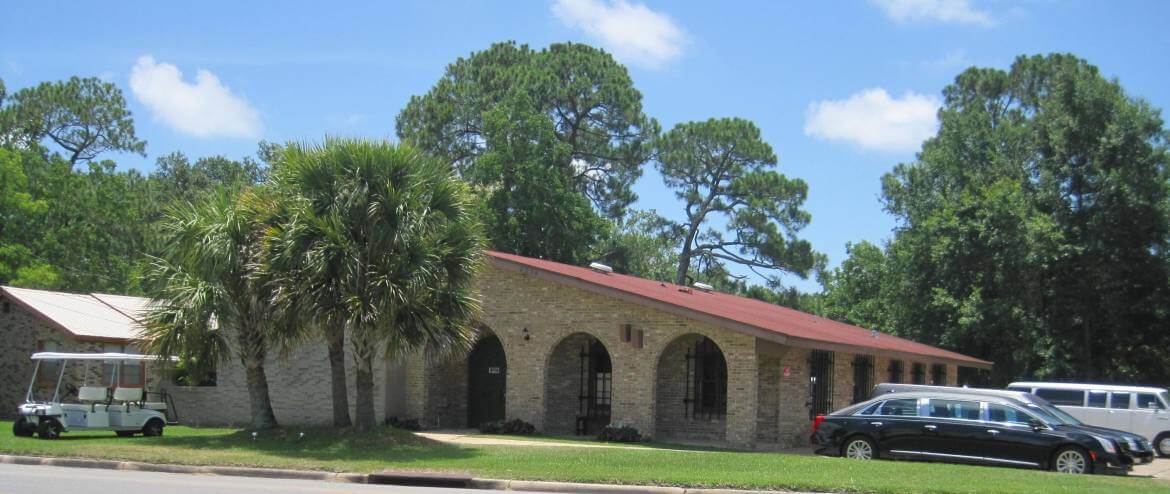 The Guardian Angels Funeral Home building on Old Mobile Avenue in Pascagoula, brick with arched entries beneath tall pines